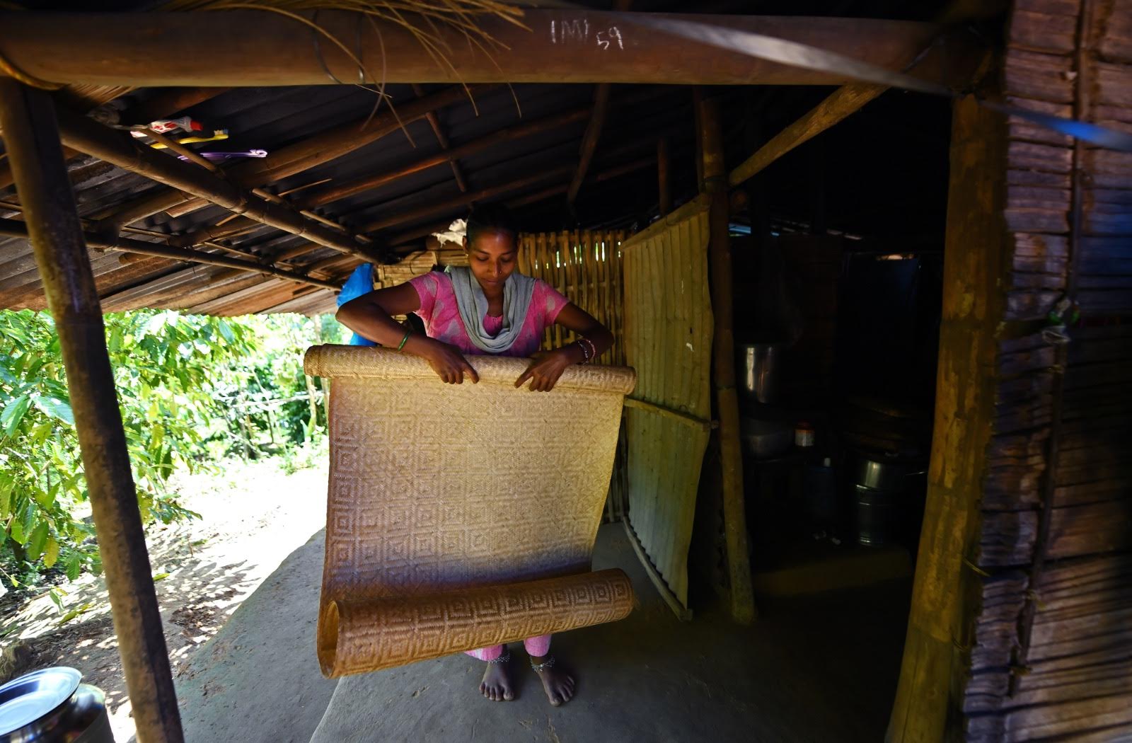 A woman in a colorful sari cooking over an open fire in a traditional Kerala kitchen.